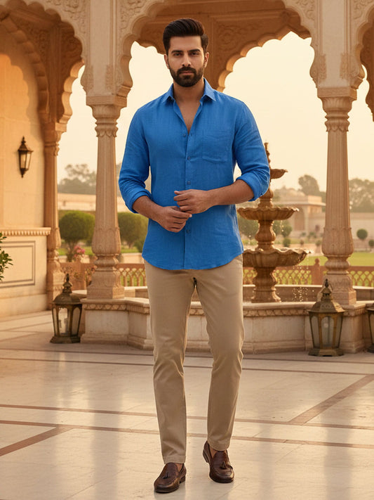 Man wearing Privee Paris Royal blue linen shirt and beige pants standing in an ornate architectural setting.